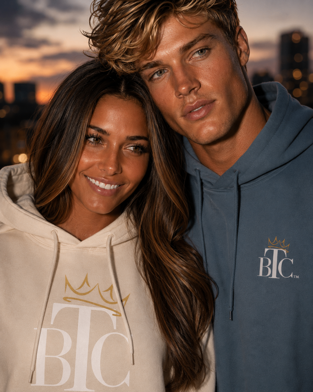 Couple in cream and blue BTC hoodies, city sunset